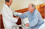 Health care provider helping elderly man out of bed